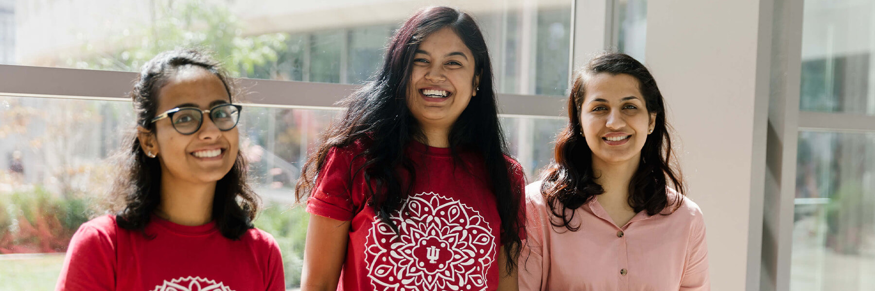 Three students posing for the camera in the HLS atrium.